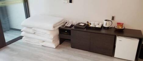 Une chambre d’hôtel équipée d’un lit, d’un petit bureau avec un téléphone, d’une machine à café et d’un mini-réfrigérateur.