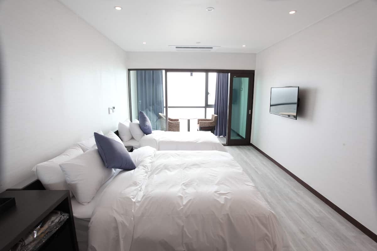 A modern hotel room with a large bed, a TV mounted on the wall, and a balcony with a view.
