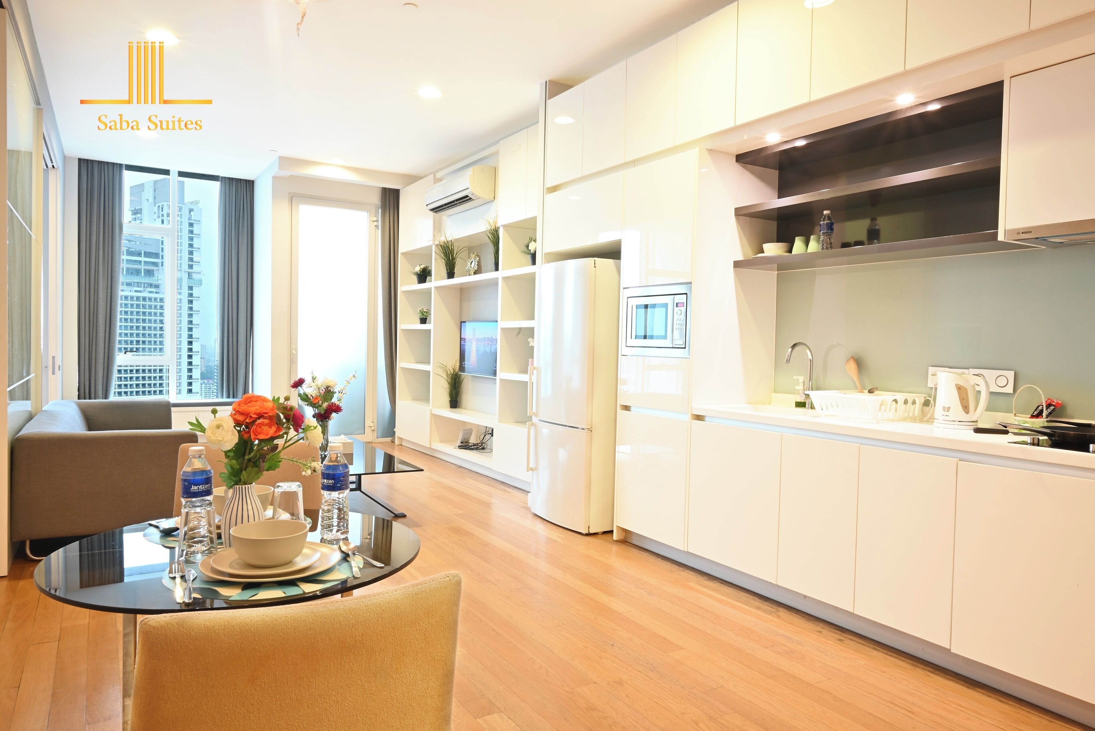 A modern kitchen with white cabinets, a built-in microwave, and a dining area with a glass table and chairs.