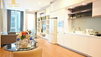 A modern kitchen with white cabinets, a built-in microwave, and a dining area with a glass table and chairs.