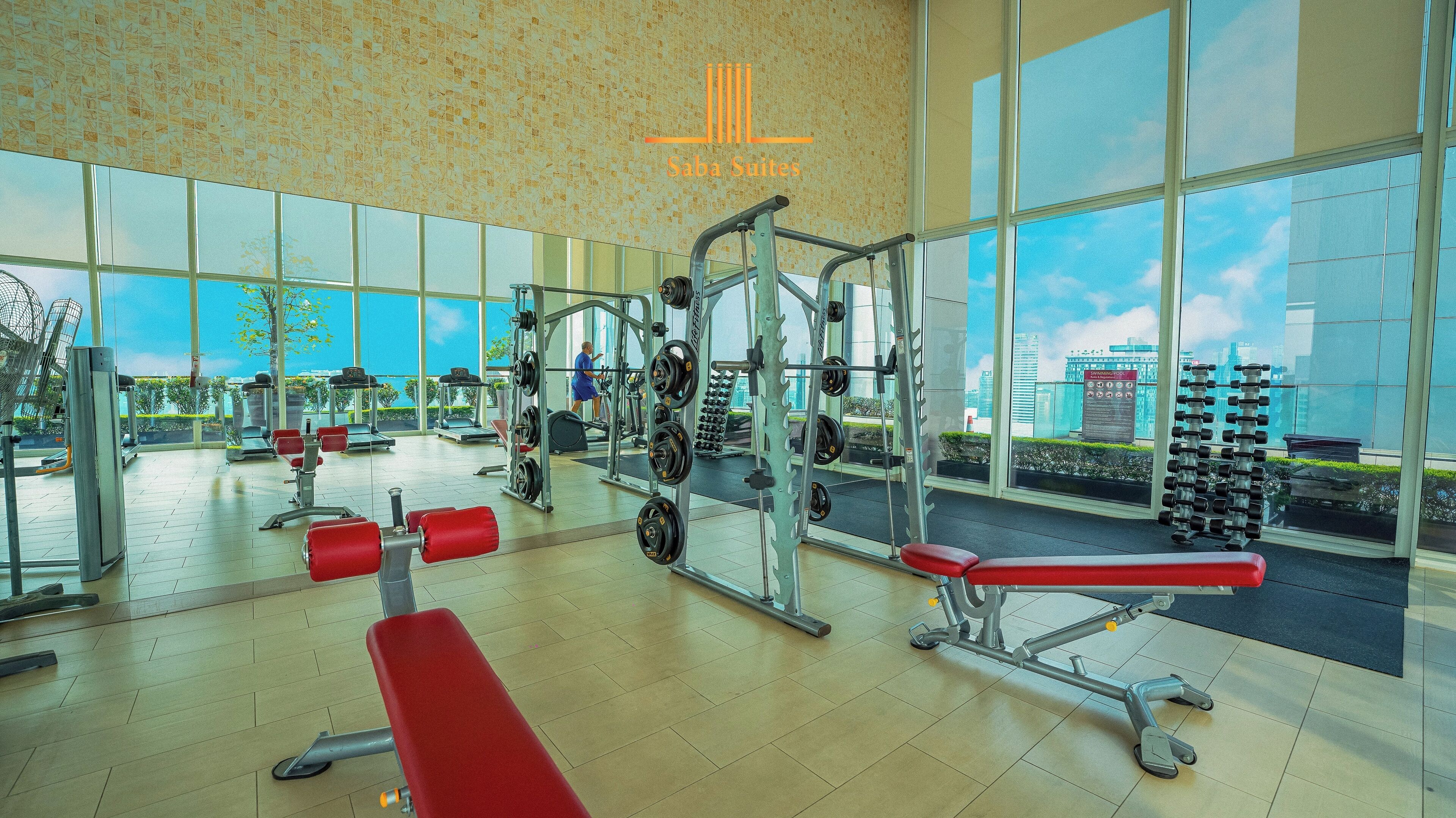 A gym with various exercise equipment, large windows, and a view of the cityscape.