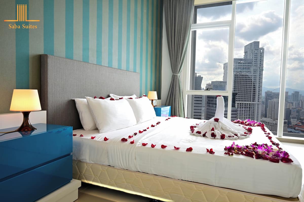 A hotel room with a large bed, two bedside tables, and a view of a cityscape through a large window.