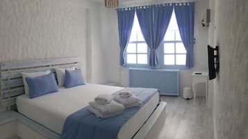 A bedroom with a bed, a radiator, a window with curtains, and a wall-mounted TV.