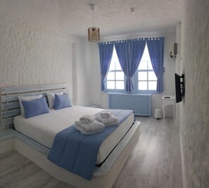 A bedroom with a bed, a radiator, a window with curtains, and a wall-mounted TV. - Thea Butik Hotel & Restaurant (Seferihisar)