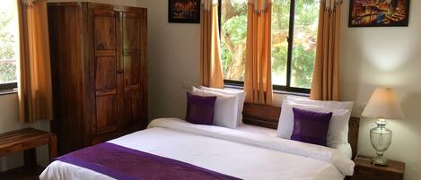 A bedroom with a large bed, wooden wardrobe, and a window with curtains.