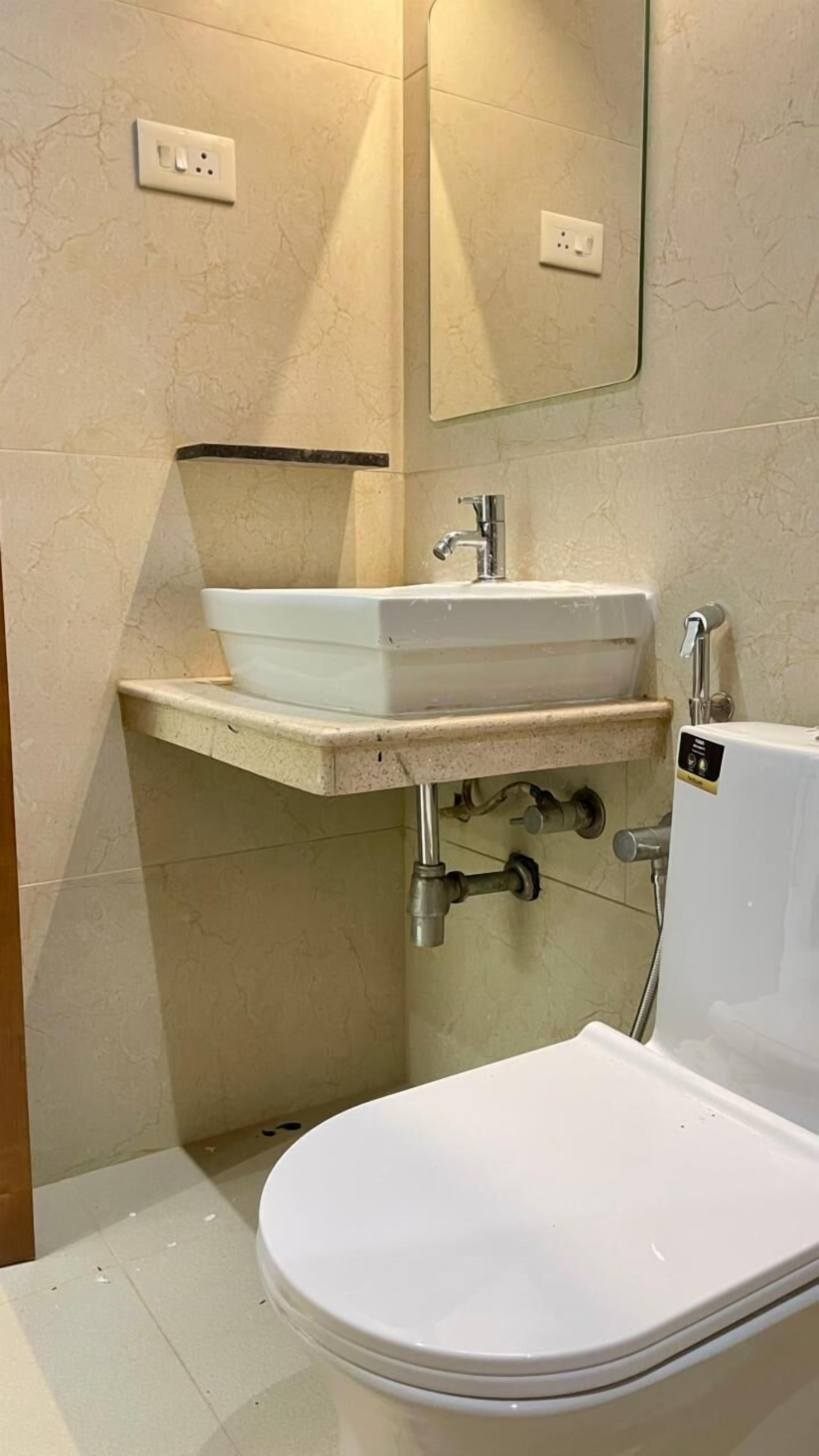 A bathroom with a white sink, a toilet, and a mirror.
