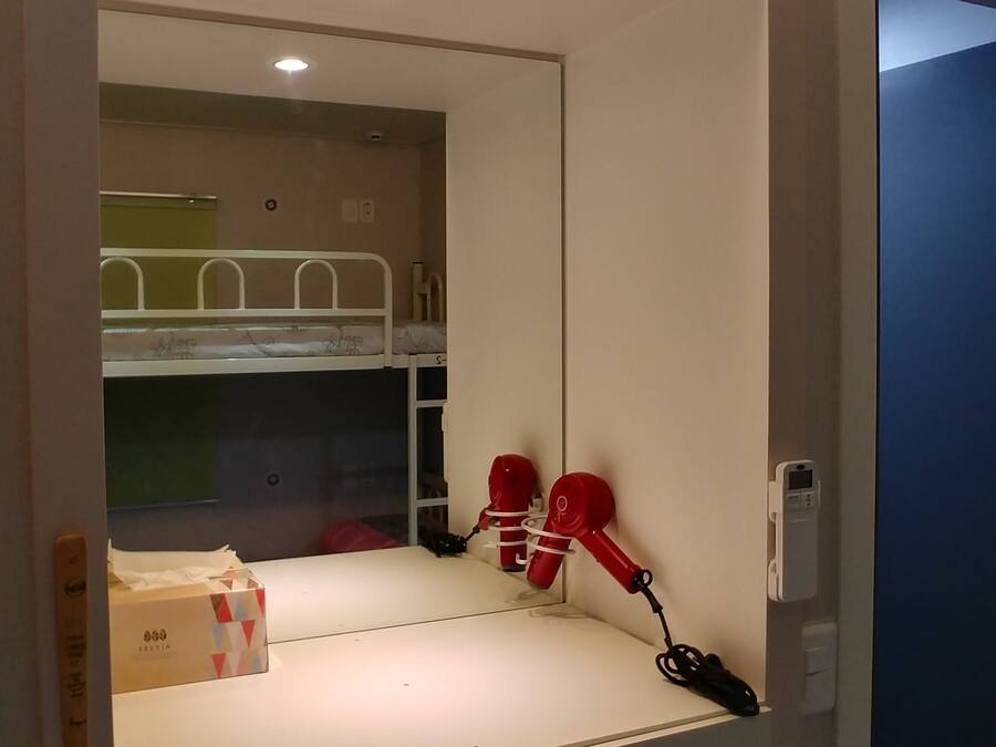 A hotel room with a bunk bed, a mirror, and a set of drawers labeled 103-1 to 103-4.