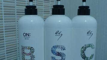 Three bottles of Elastine body wash, shampoo, and conditioner on a glass shelf.