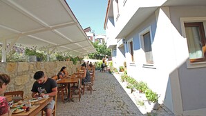 Un café en plein air avec un sol en pierre et des tables et des chaises en bois.