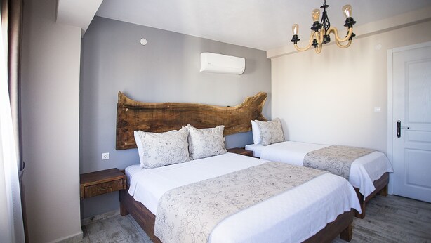 Une chambre avec deux lits, une tête de lit en bois, un lustre et une porte blanche.