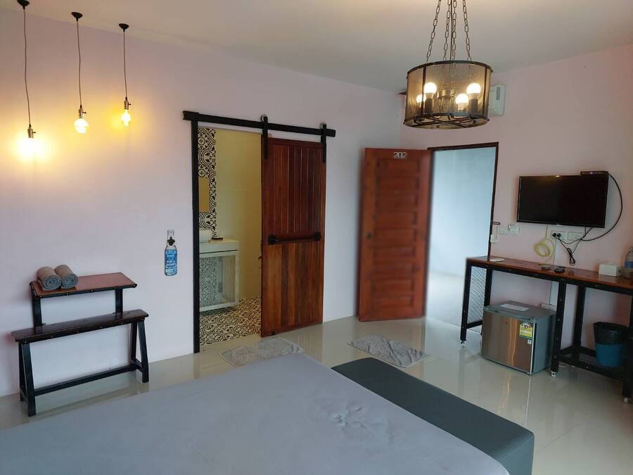 A bedroom with a bed, a desk, a TV, and a sliding door.