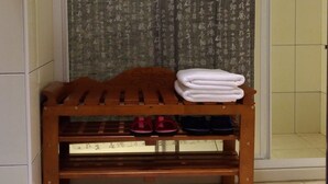Un banc en bois avec des serviettes pliées, un rideau orné de caractères chinois et un sol carrelé.