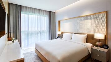 A hotel room with a large bed, bedside tables, a desk, and a view of the outdoors.