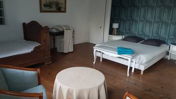 Ein Zimmer mit einem Bett, einem Sessel, einem Tisch und einem Bild an der Wand.