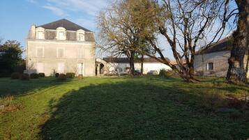 A large, historic building with a symmetrical facade, a central entrance, and a well-maintained lawn.