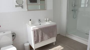 A modern bathroom with a white sink, mirror, and toilet.