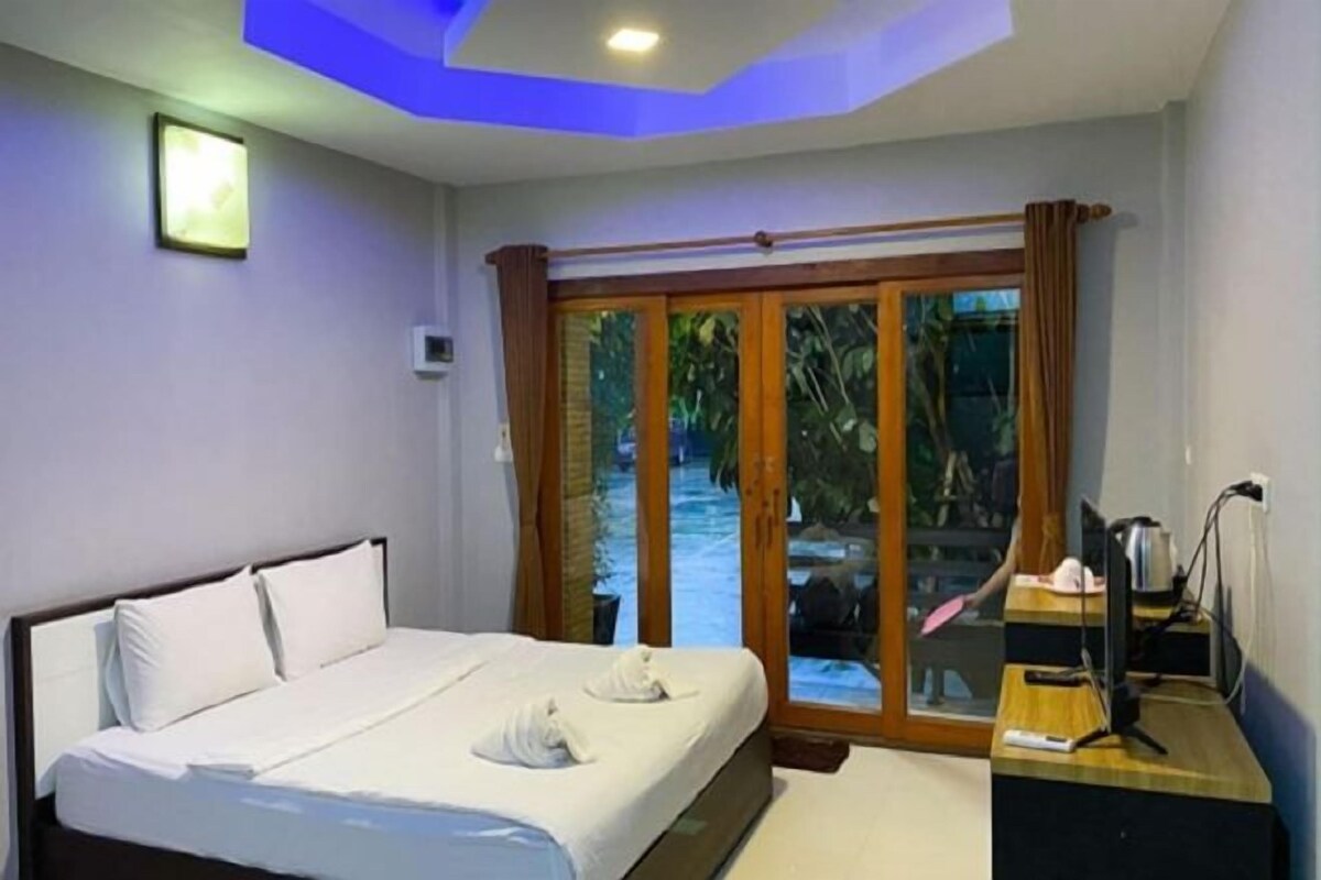 A hotel room with a bed, a desk, a computer, and a view of an outdoor swimming pool.