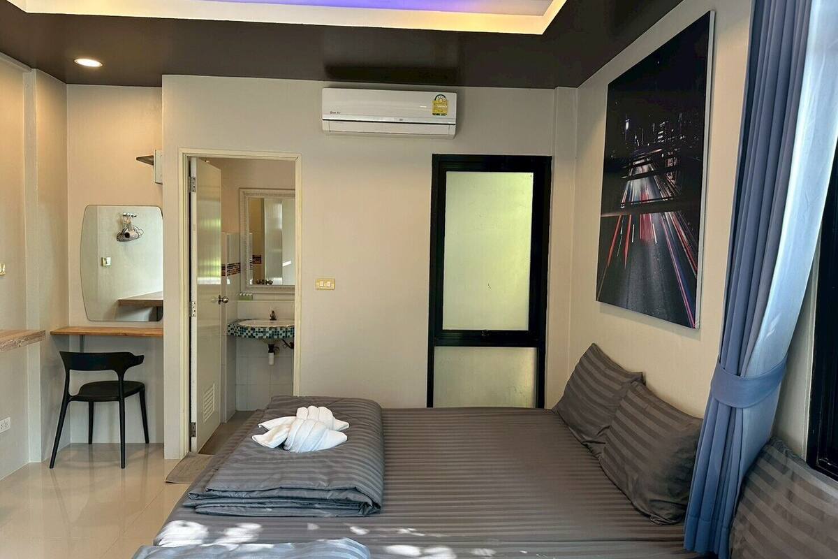A modern hotel room with a bed, a desk, and a bathroom.
