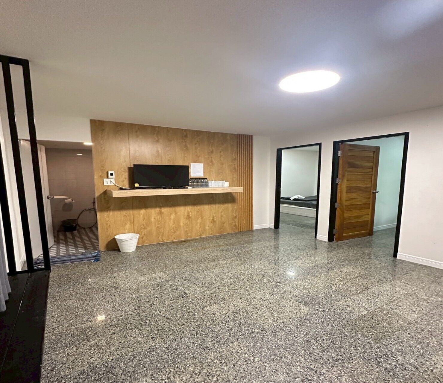 Une chambre d’hôtel moderne avec un comptoir d’accueil en bois, un téléviseur à écran plat et une petite poubelle.