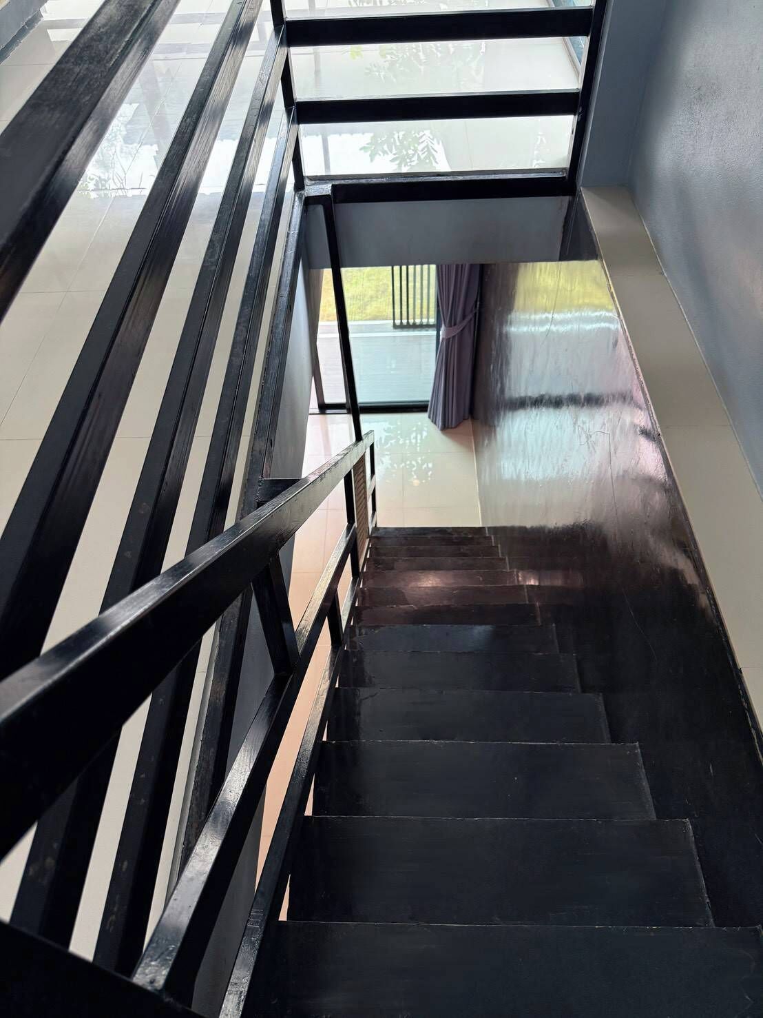 Una escalera con barandillas negras que lleva a un rellano con una puerta de vidrio.