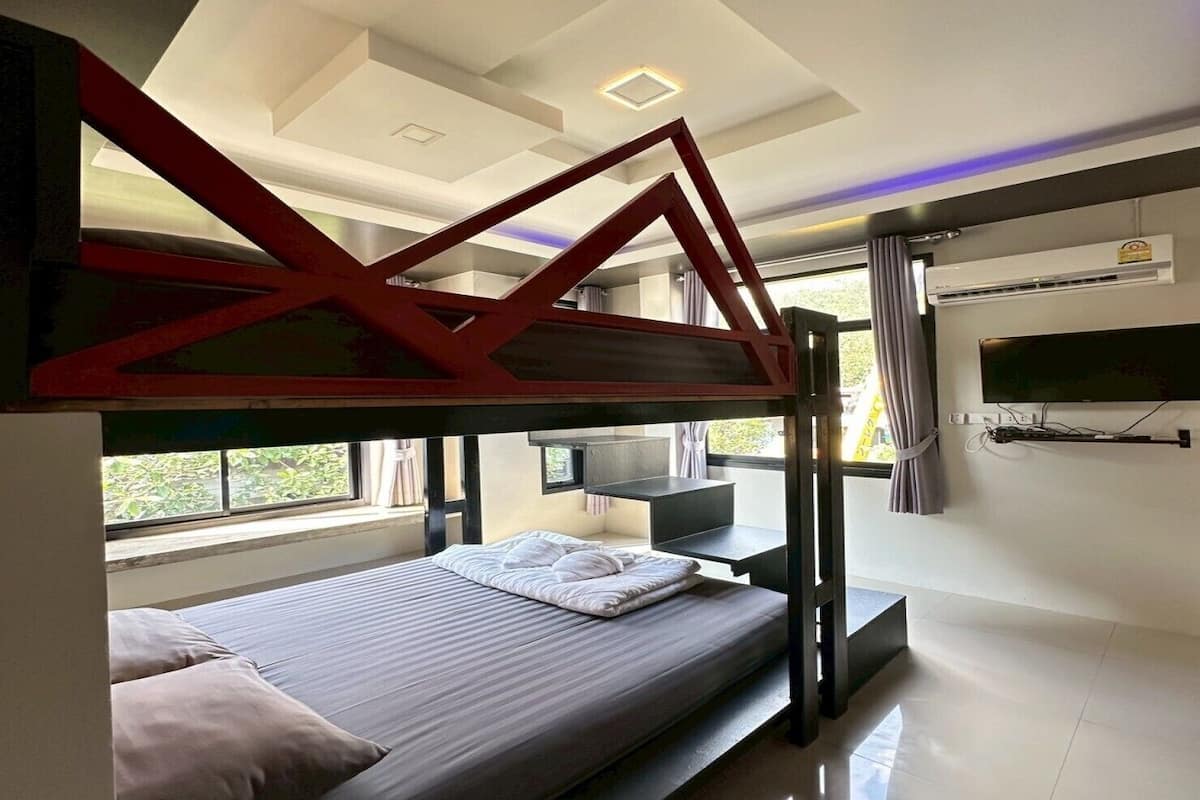 A bunk bed room with a TV, a small table, and a window with curtains.