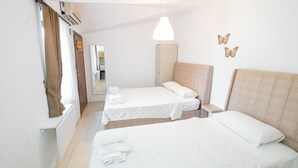 Habitación de hotel con dos camas, un espejo, una lámpara colgante y decoración de mariposas en la pared.