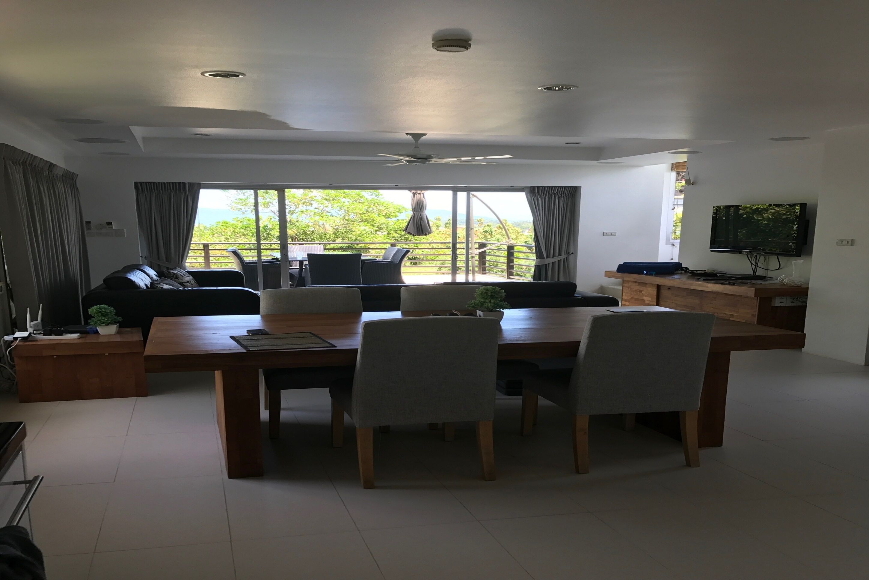 A modern living room with a dining table, chairs, a sofa, and a TV.