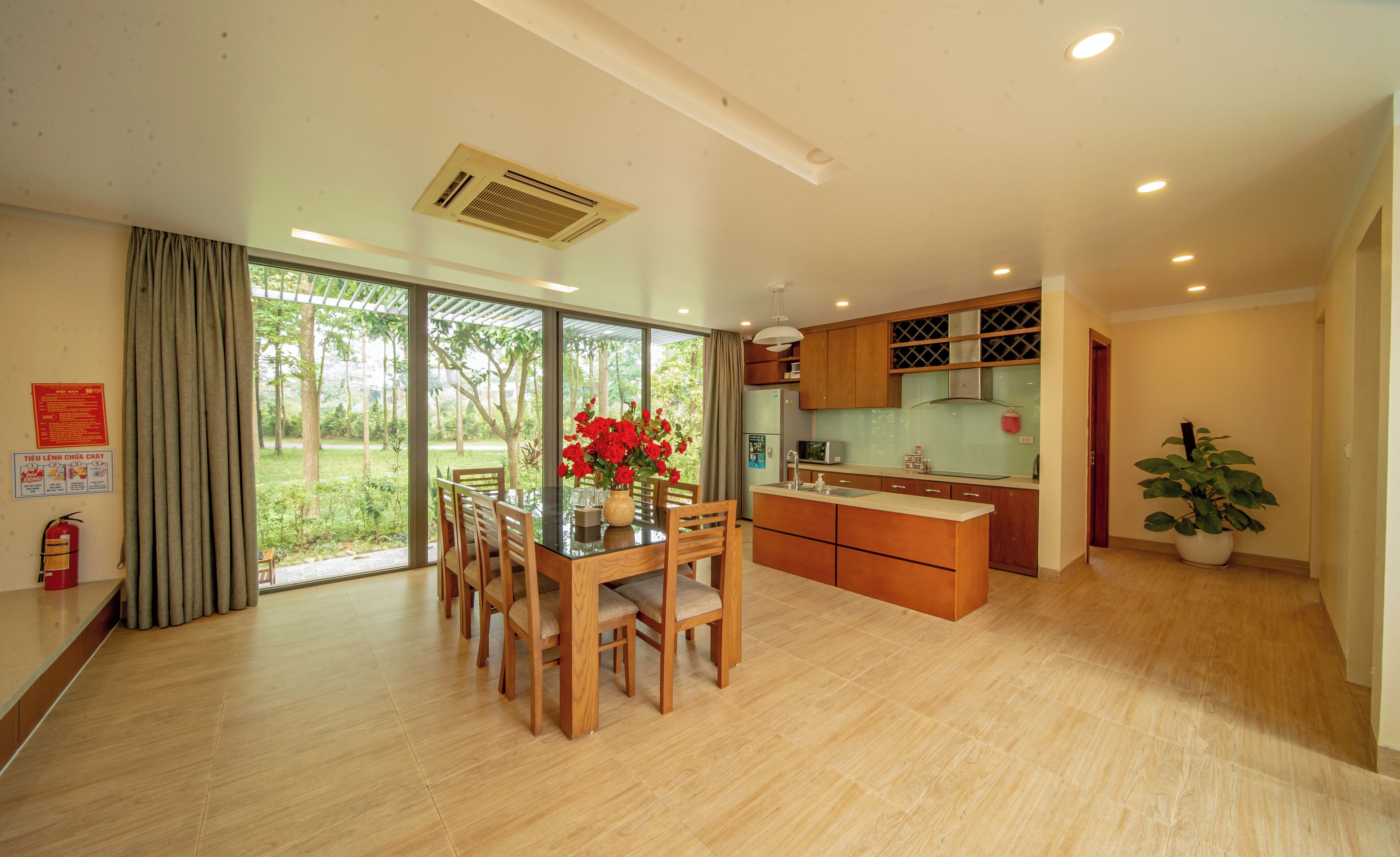 A modern kitchen with wooden cabinets, a central island, and a dining area with a table and chairs.