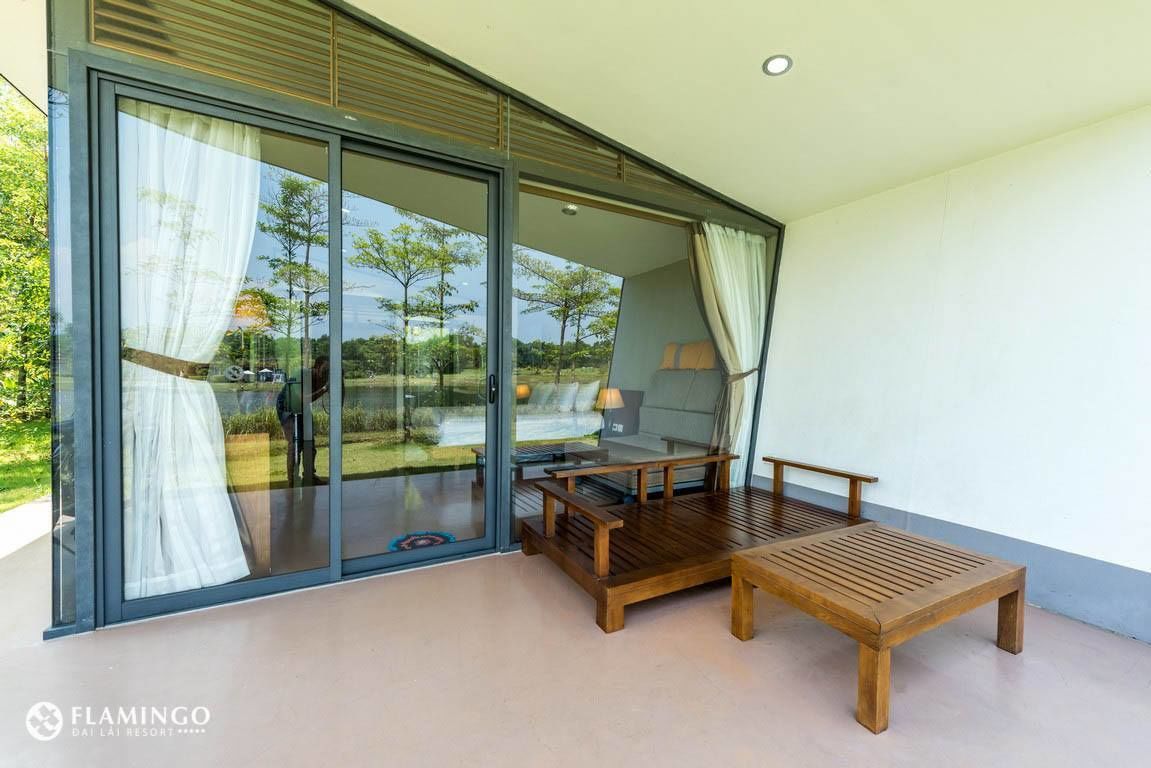 Une chambre moderne dotée d’une grande porte-fenêtre coulissante donnant sur un espace extérieur, d’un banc en bois et d’une petite table.