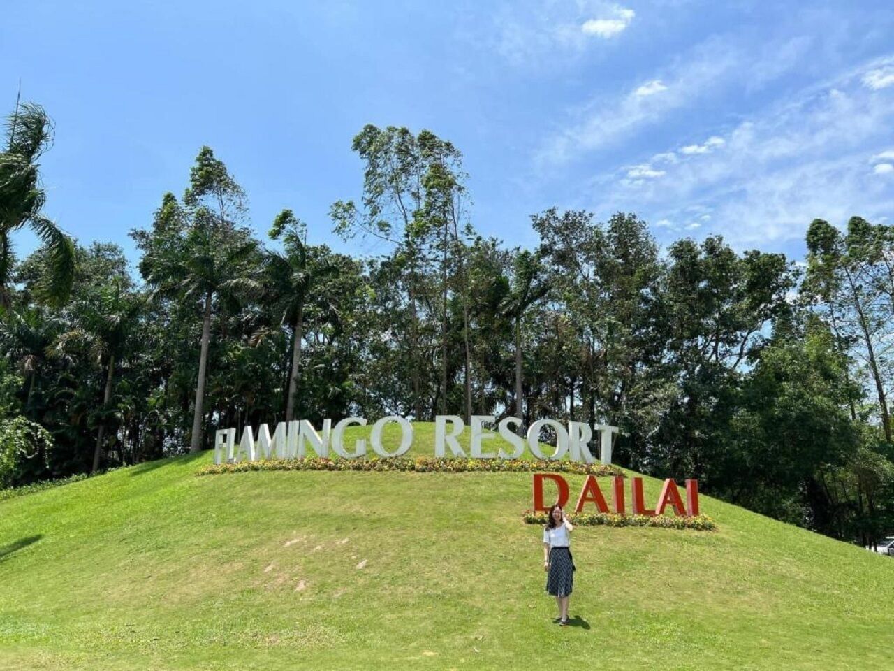 A sign for FAMINGO RESORT in DAILA with a person standing in front.
