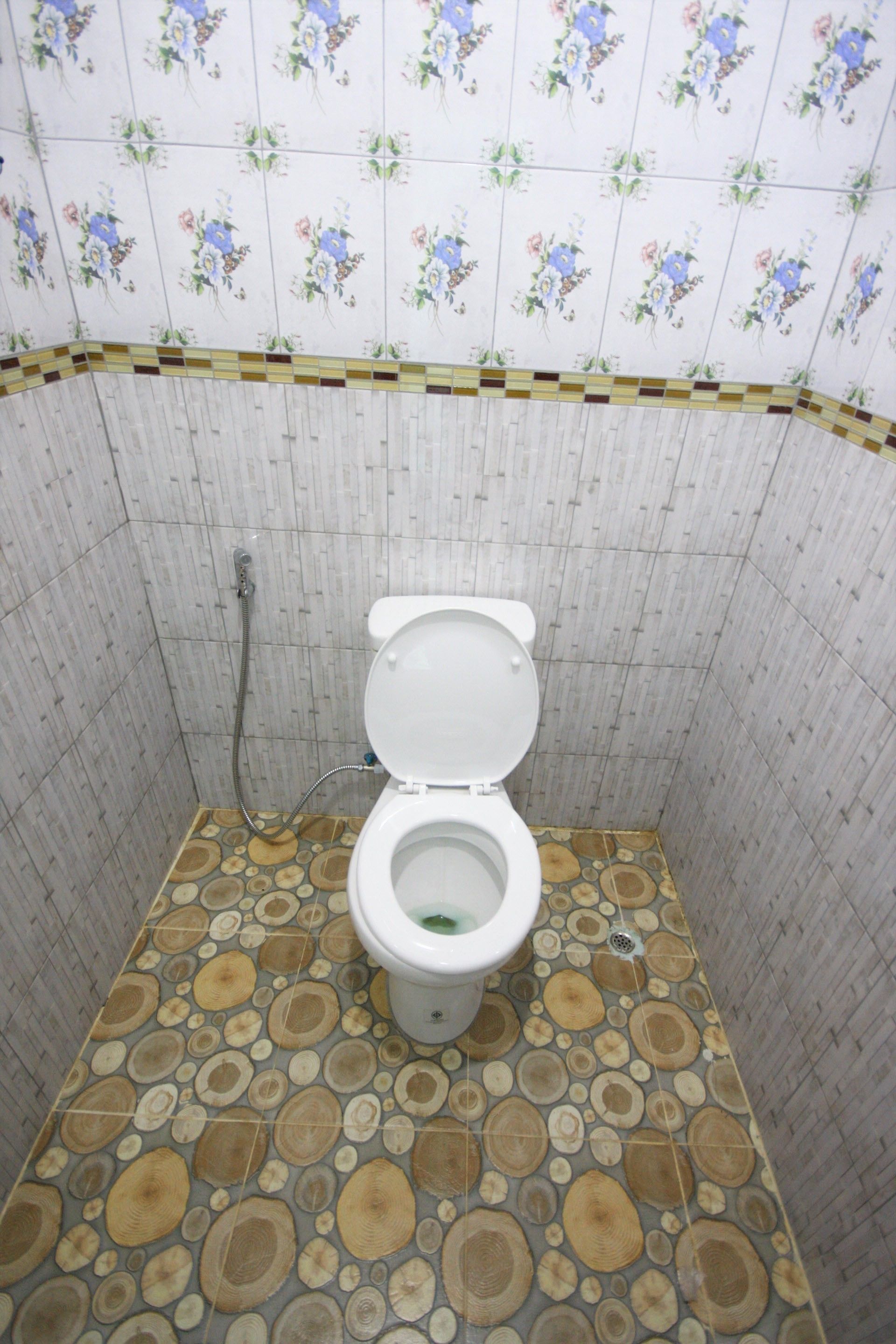 Une salle de bain avec des toilettes, une douche et des carreaux de sol à motifs.