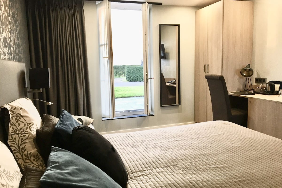 Una habitación de hotel moderna con una cama grande, un escritorio, una silla y vistas al exterior.