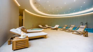 A spa area with a pool, sun loungers, and a wooden bench with candles.