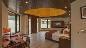 A hotel room with a bed, a desk, a chair, a TV, and a large window.
