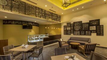 Un restaurante con techo alto, menús expuestos en la pared y diferentes opciones de asientos, incluyendo mesas y sillas.