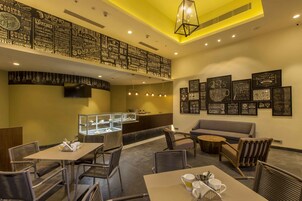 Un restaurante con techo alto, menús expuestos en la pared y diferentes opciones de asientos, incluyendo mesas y sillas.
