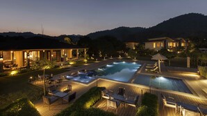 A resort with a swimming pool, outdoor seating, and a well-lit patio area.