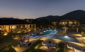 A resort with a swimming pool, outdoor seating, and a well-lit patio area.