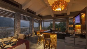 A modern interior with a bar area, seating, and large windows offering a view of the outdoors.