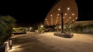 An outdoor area with a modern, uniquely shaped building illuminated by numerous lights.