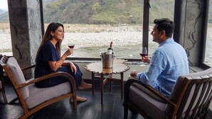 Two people seated at a table with a view of a lake and hills.
