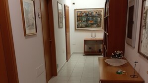 A hallway with a tiled floor, wooden doors, and framed artwork on the walls. - Copenaghen House (Sassari)