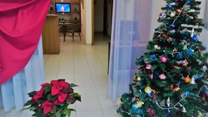 A living room with a Christmas tree, a television, and a dining area. - Copenaghen House (Sassari)