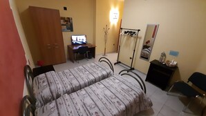 A bedroom with two beds, a desk, a wardrobe, a mirror, and a radiator. - Copenaghen House (Sassari)