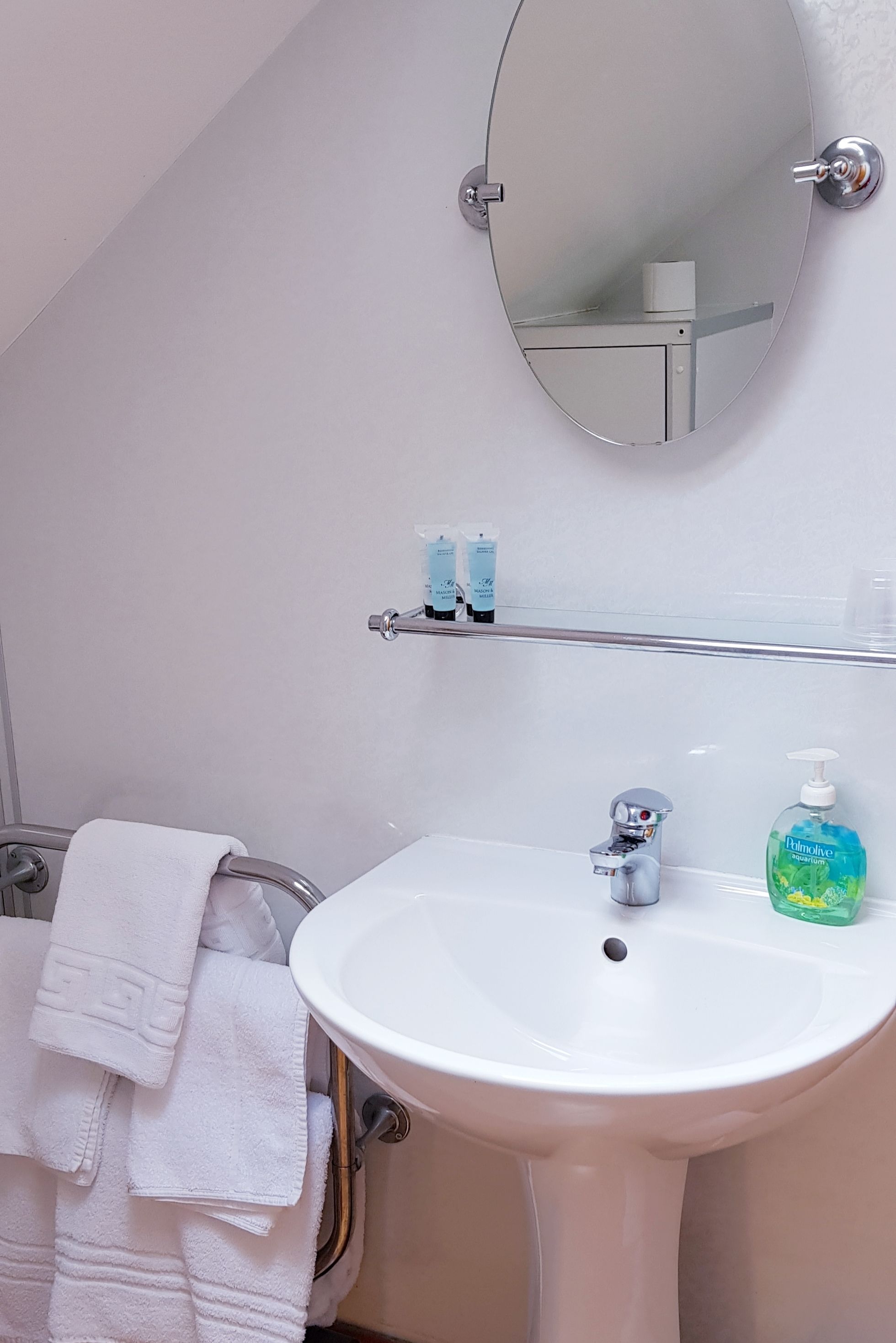 A bathroom with a white sink, a mirror, and a towel rack.