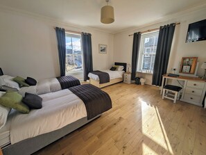 A bedroom with two beds, a desk, and a window with curtains.