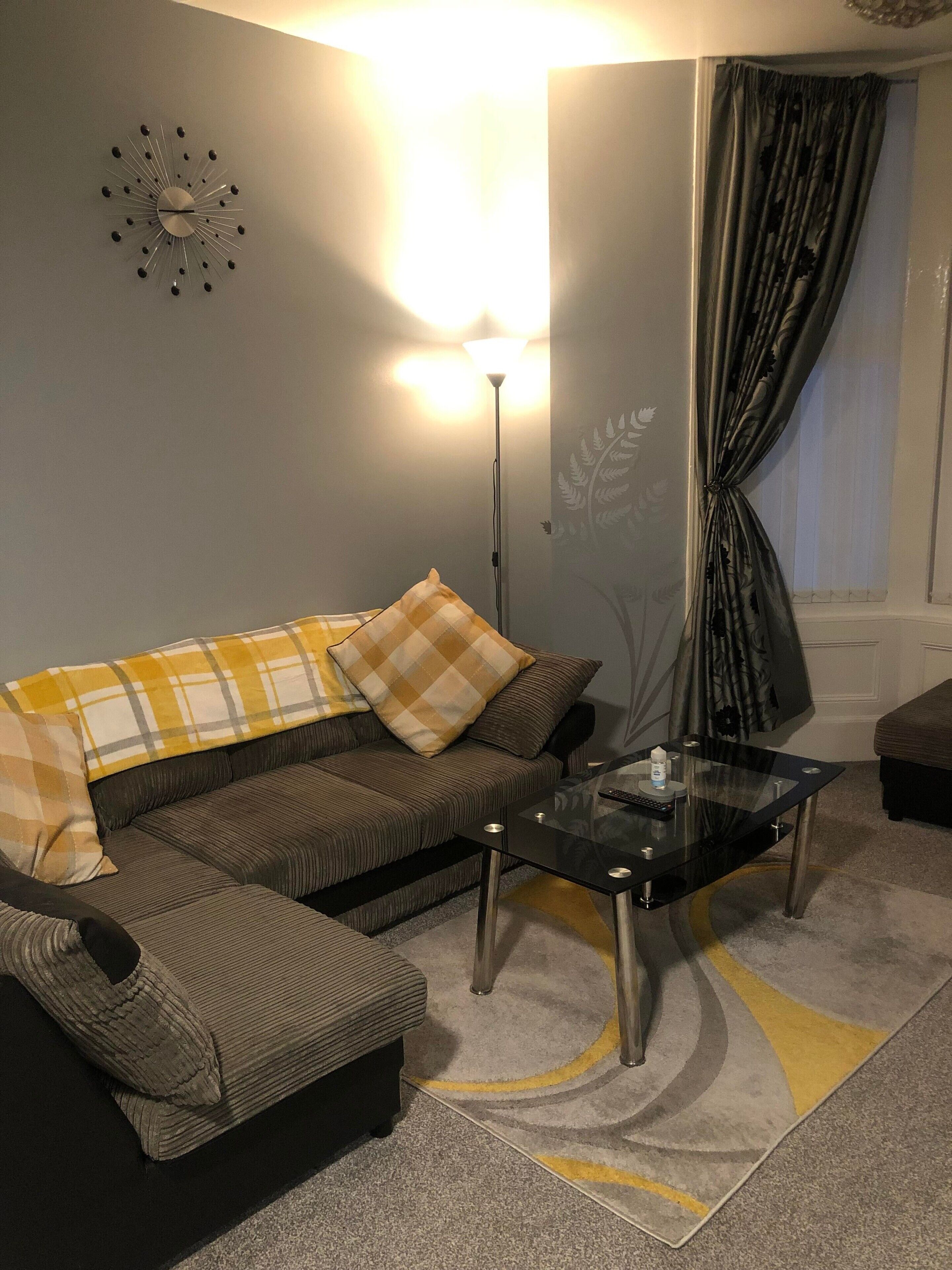 Un salon comprenant un canapé, une table basse en verre, une lampe sur pied et un tapis à motifs.