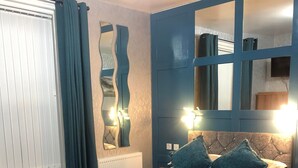 Um quarto com cama, sofá, cómoda e espelho.