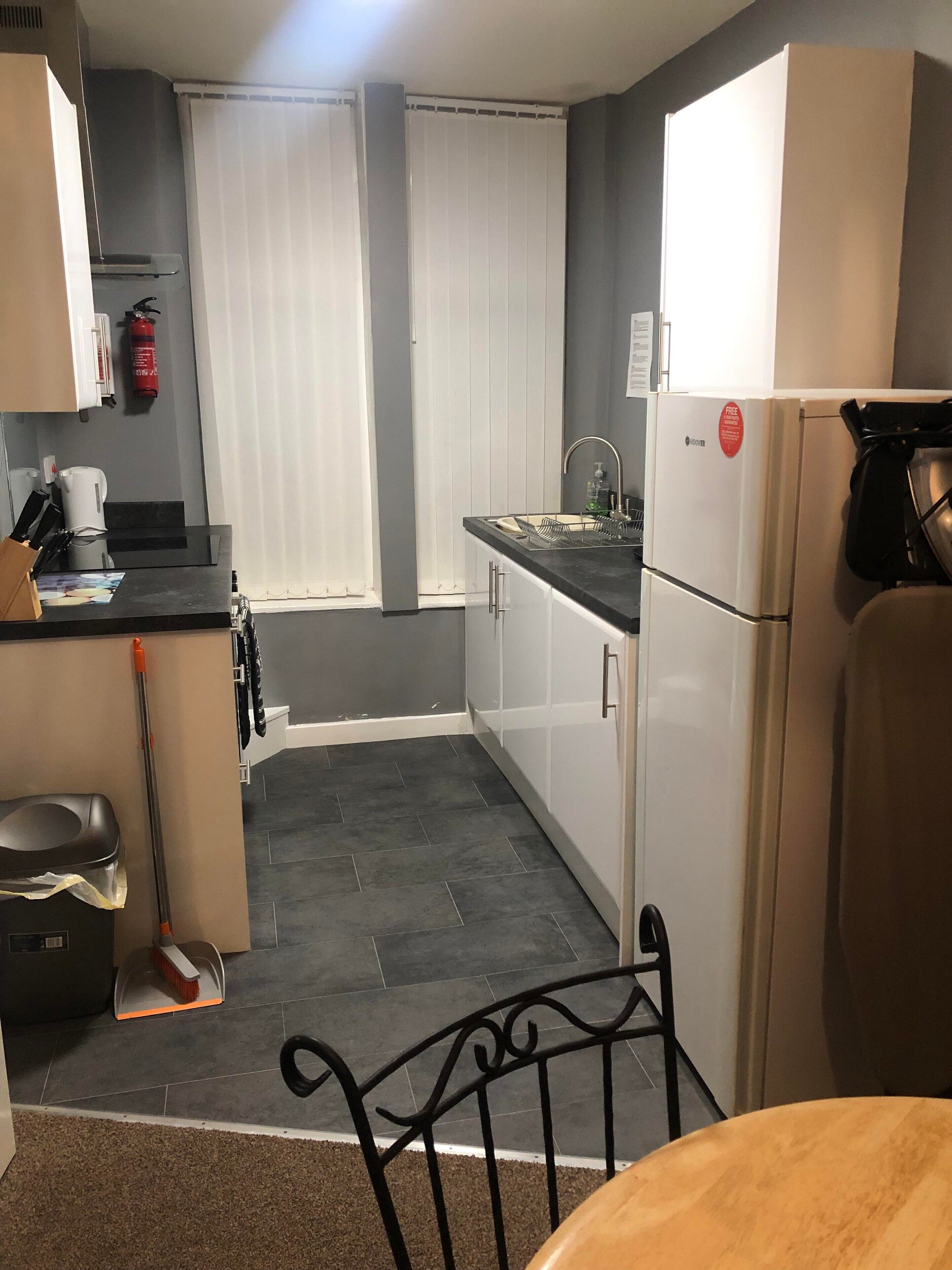 A compact kitchen with a refrigerator, sink, and a coffee maker.