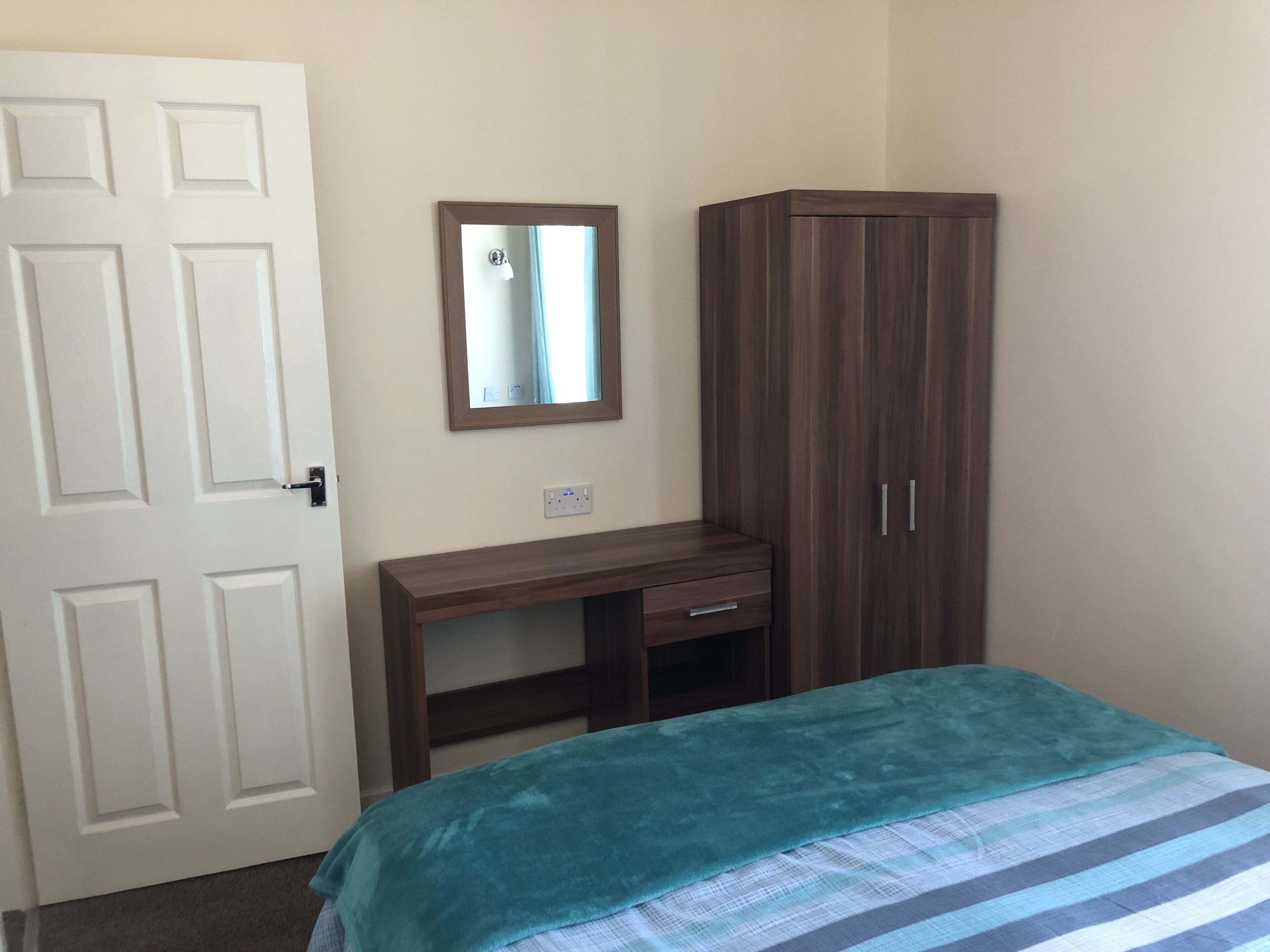 Une chambre à coucher avec un lit, une armoire, un bureau et un miroir.